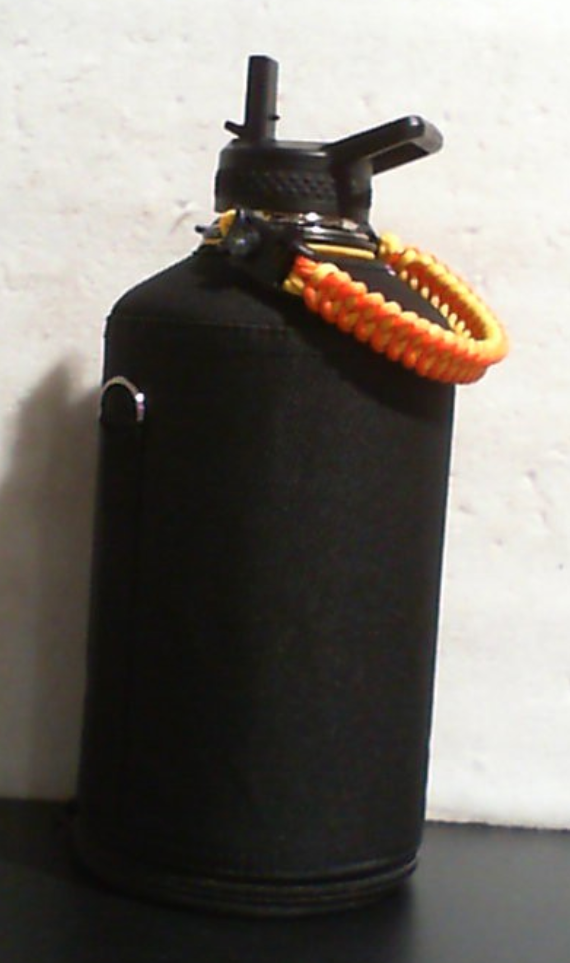 Botella negra con funda y asa trenzada naranja para llevar tu agua
