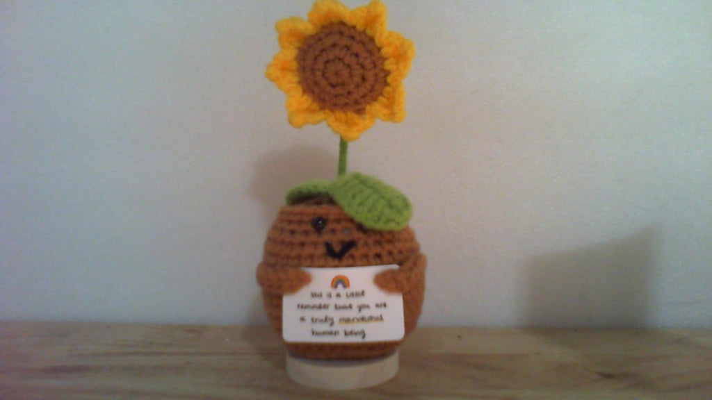 muñeco sonriente y un girasol hechos de lana.