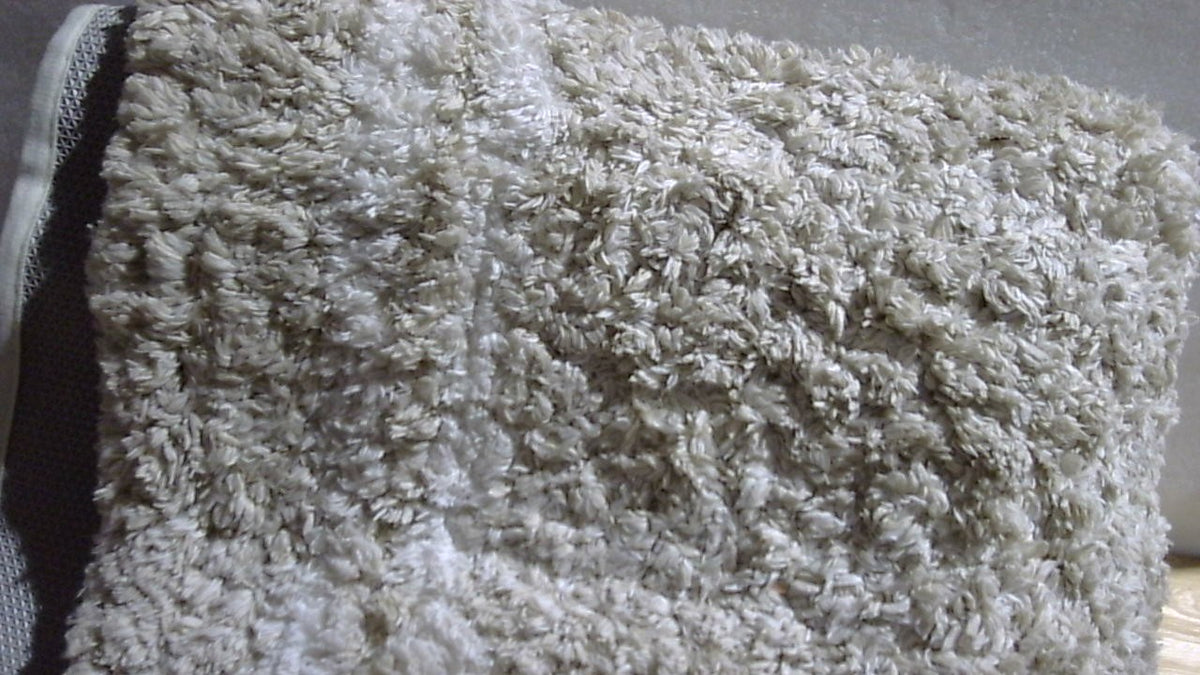 Alfombra rectangular color crema con textura de pelo y diseño geométrico
