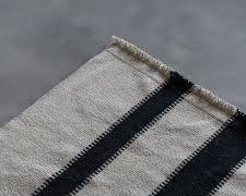alfombra tejida de algodón o lana con un patrón de rayas negras sobre un fondo caqui, beige o natural ( DISENO IGUAL A LA SEGUNAD IMAGEN )