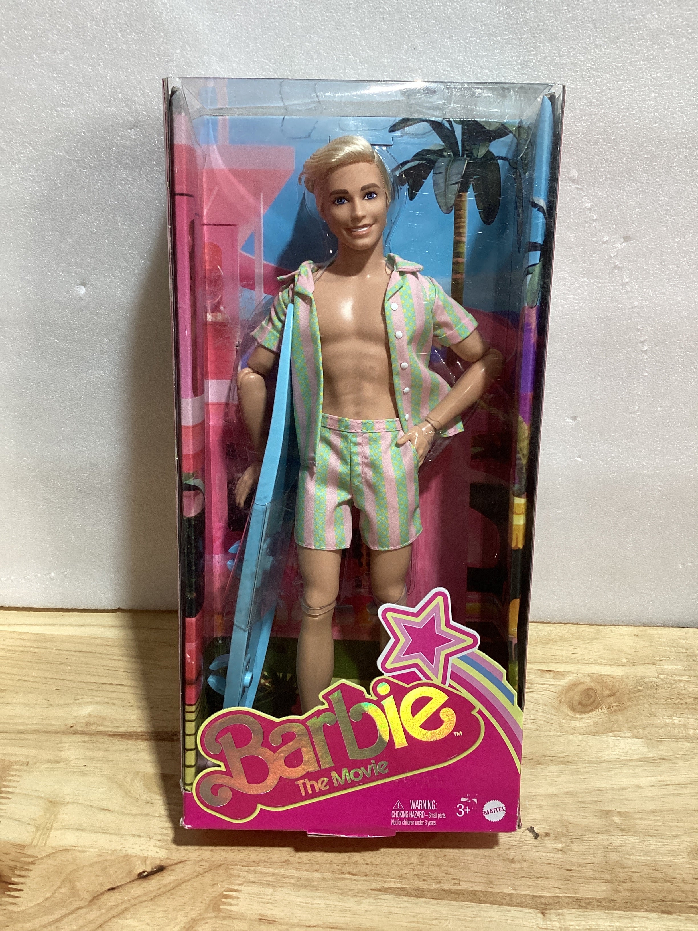Muñeca Ken de la película Barbie, colección con traje de playa a rayas en colores rosa pálido y verde con tabla de surf y zapatillas blancas